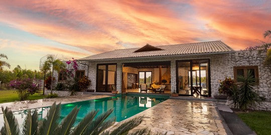 Luxury home with a pool and stone exterior during sunset.